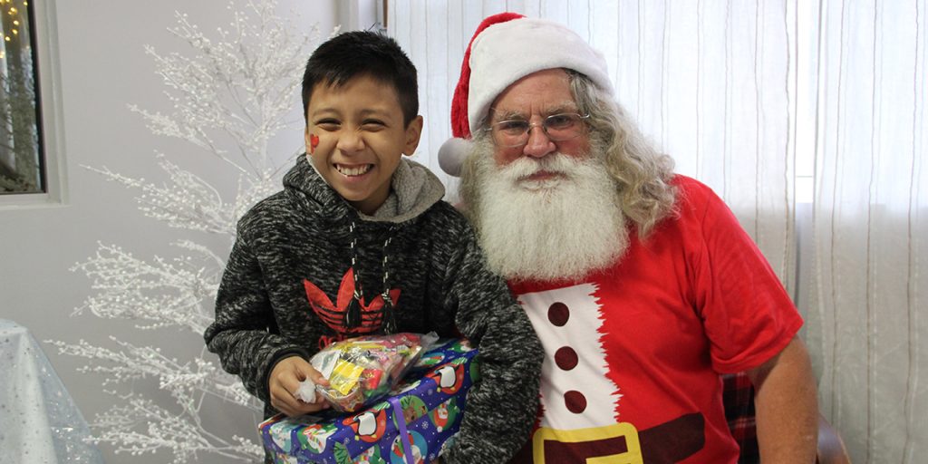 A kid with their gift and Santa at our Christmas fiesta at our clinic in Reynosa Mexico